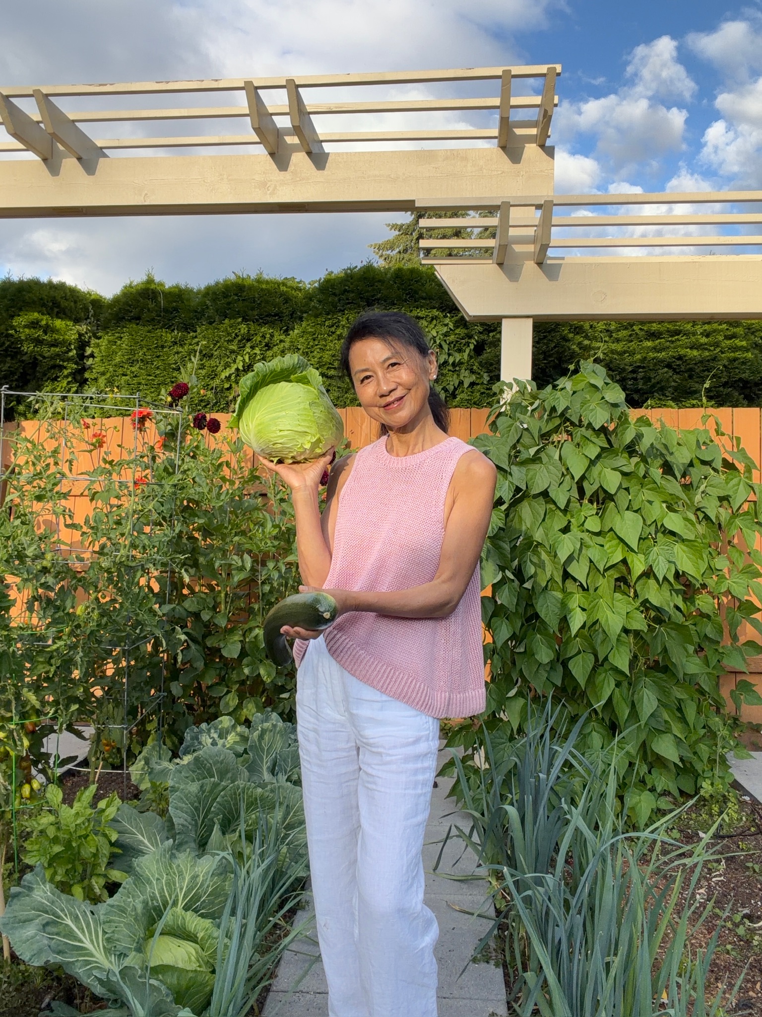 Janney on the path holding a cabbage and a zucchini she just picked